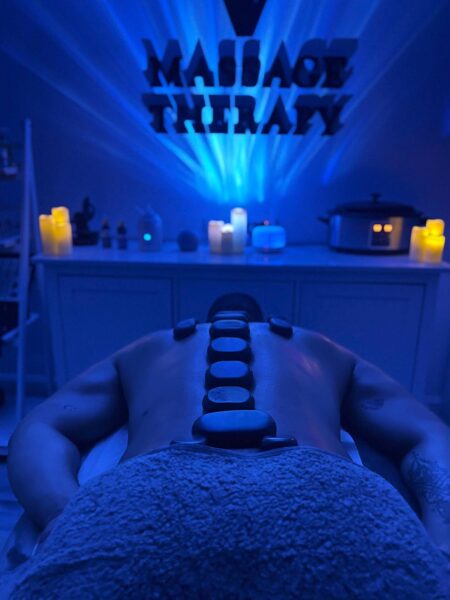 Hot stones on mans back in a darkened room